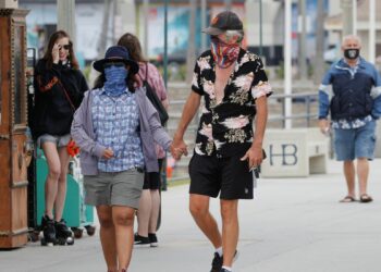 Pessoas que usam máscaras caminham ao longo do cais do oceano enquanto os Estados Unidos passaram na quinta-feira um total de mais de 4 milhões de infecções por coronavírus durante o surto global da doença por coronavírus (COVID-19) em Huntington Beach, Califórnia, EUA, em 23 de julho de 2020 REUTERS / Mike Blake